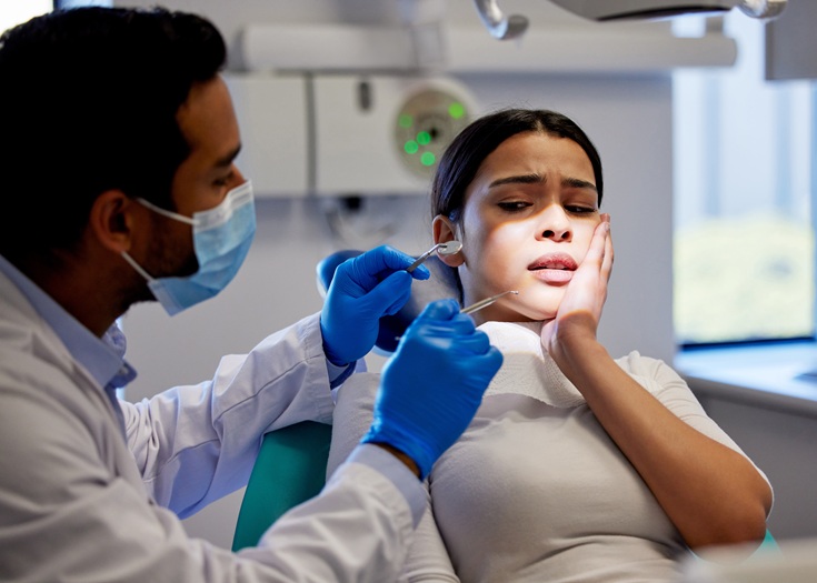 A woman sitting Infront of emergency dentist because of she has dental pain